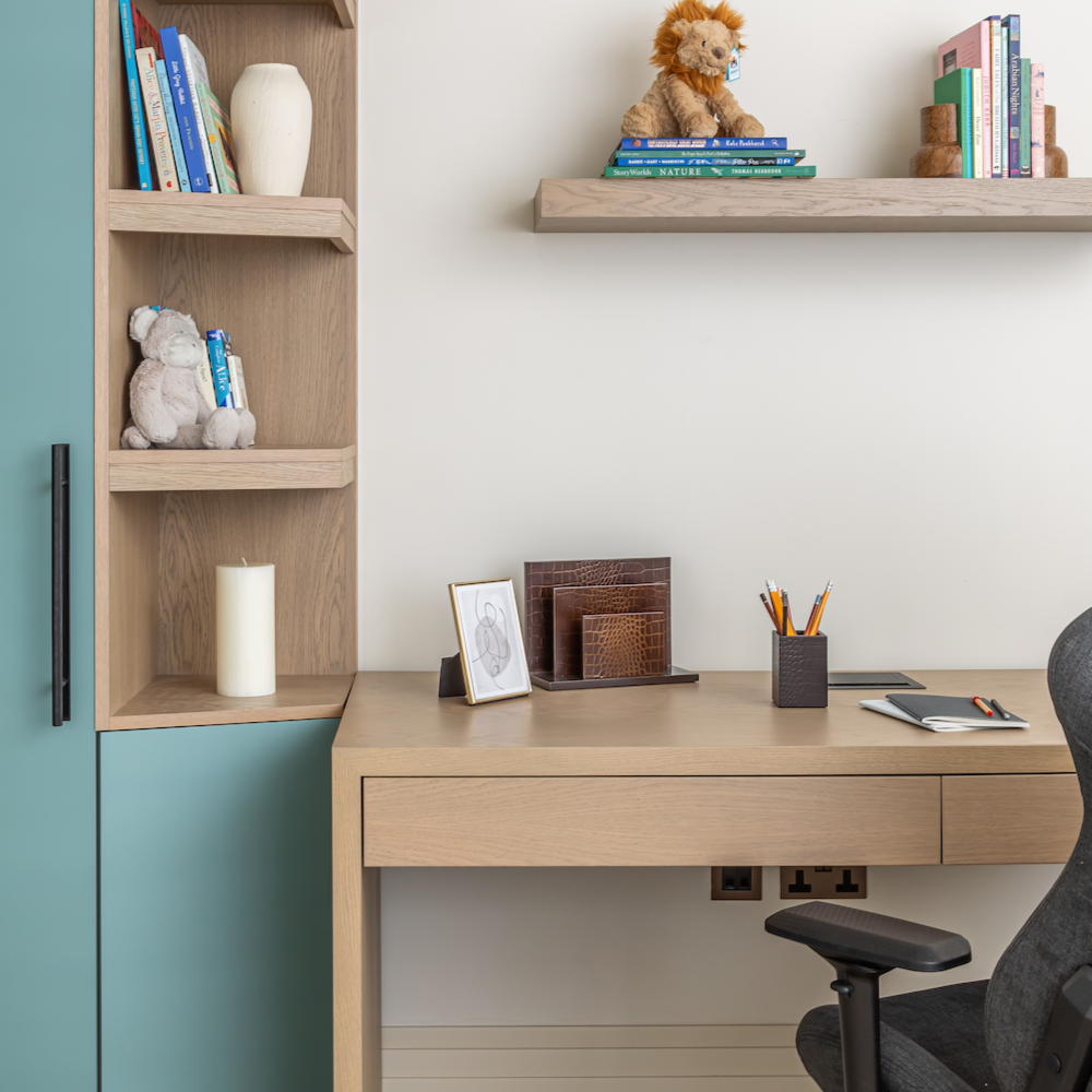 Modern home office with wooden desk, shelves, and chair against a light blue wall.