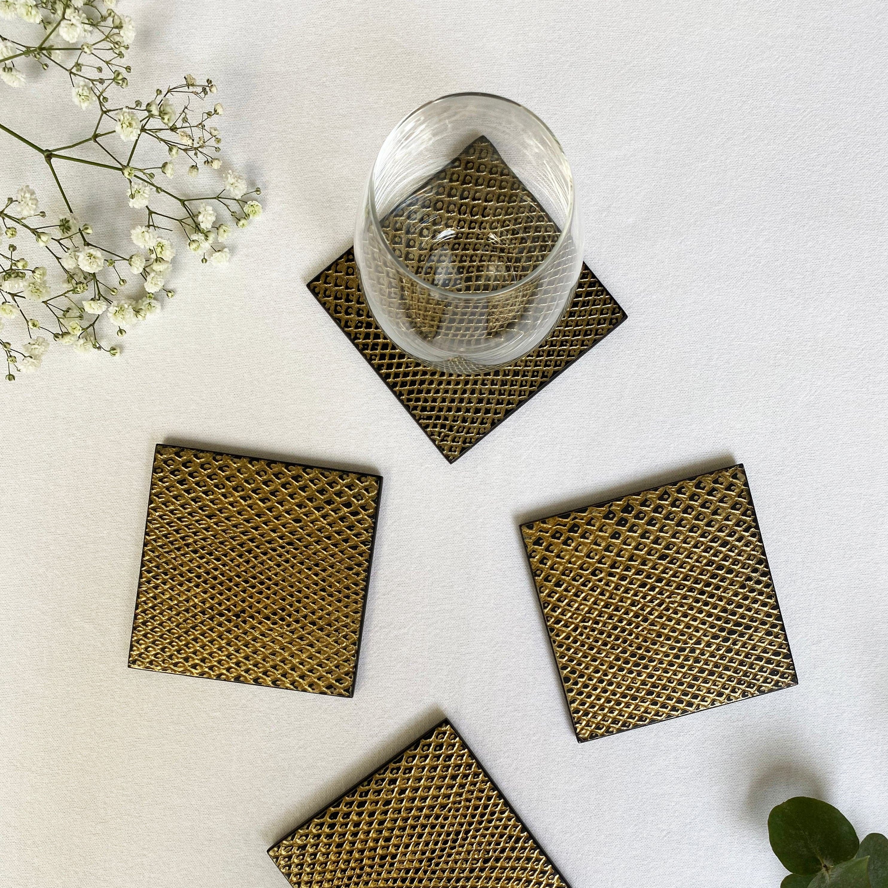 Set of woven coasters with a glass on a light surface with plants.