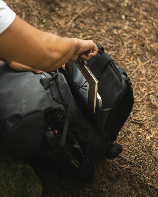 person in black shirt and black pants sitting on black leather backpack