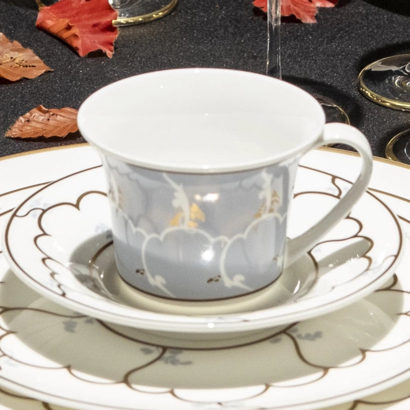Dining table set with elegant dinnerware, glasses, and cutlery on a black surface.