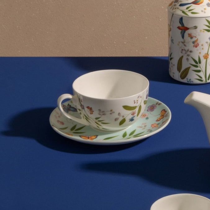 Tea set with floral patterns on a blue table against a beige background