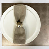 White plate with a folded gray napkin on a metallic surface